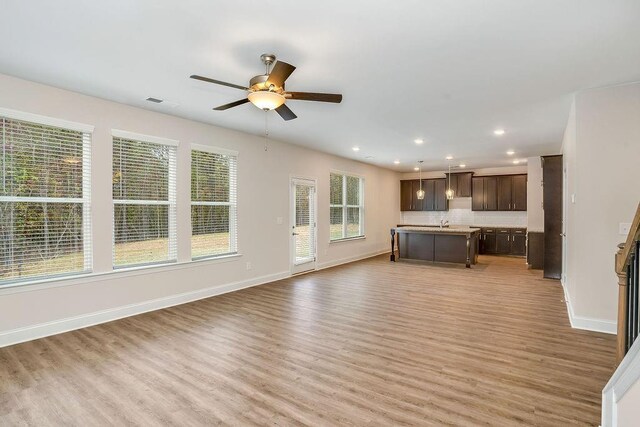 201 Cooper Dr, Mansfield, GA 30055 - unfurnished living room featuring a ceiling fan, light wood-style floors, baseboards, recessed lighting, and a sink
