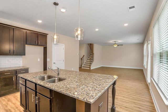 kitchen featuring decorative backsplash, light hardwood / wood-style floors, ceiling fan, and sink