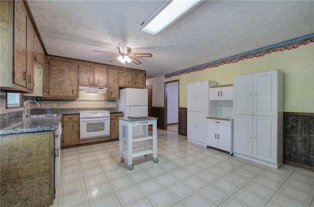 kitchen with under cabinet range hood, electric range, a sink, freestanding refrigerator, and light floors