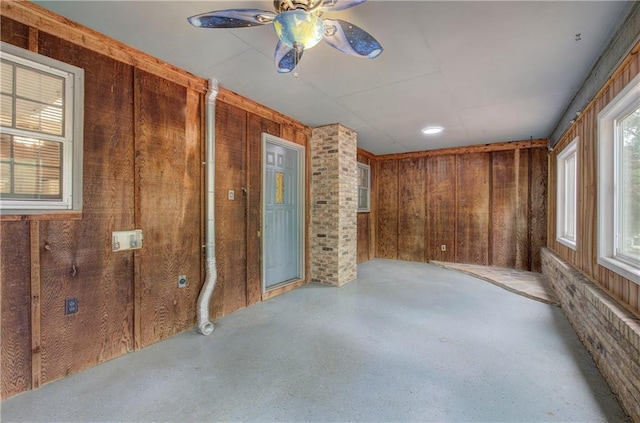 unfurnished room with a ceiling fan and wooden walls