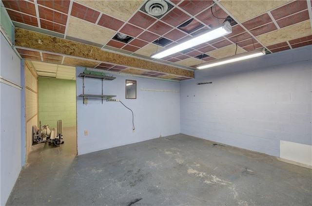 below grade area featuring visible vents, a paneled ceiling, and concrete block wall