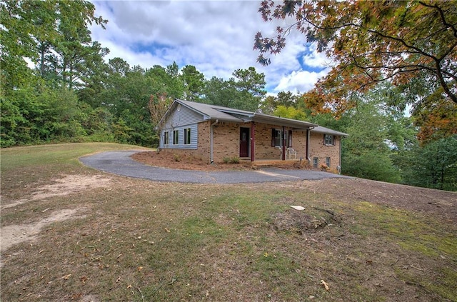 single story home featuring a front yard, brick siding, and driveway