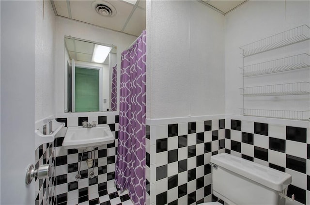 bathroom with toilet, visible vents, a drop ceiling, and a sink