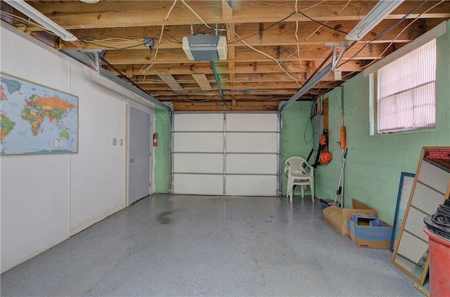 garage featuring concrete block wall and a garage door opener