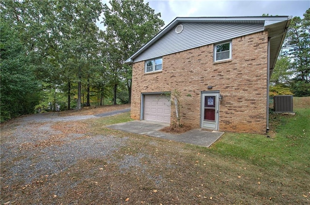 rear view of house with driveway, a garage, central AC, and brick siding