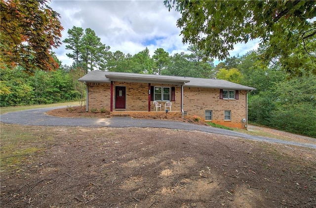 single story home featuring driveway, a porch, and brick siding