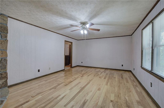 empty room featuring a textured ceiling, wood finished floors, a ceiling fan, and crown molding