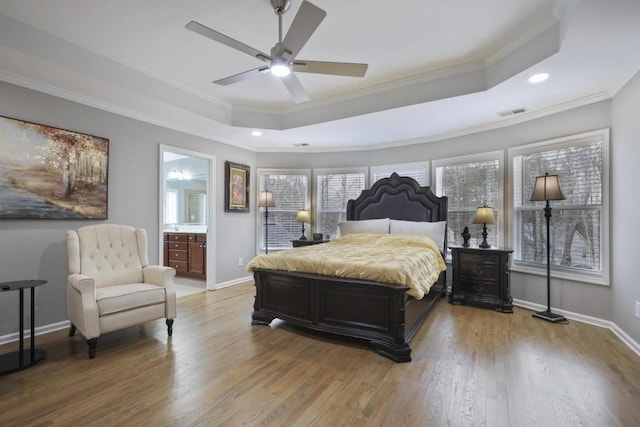 bedroom featuring a raised ceiling, crown molding, baseboards, and wood finished floors