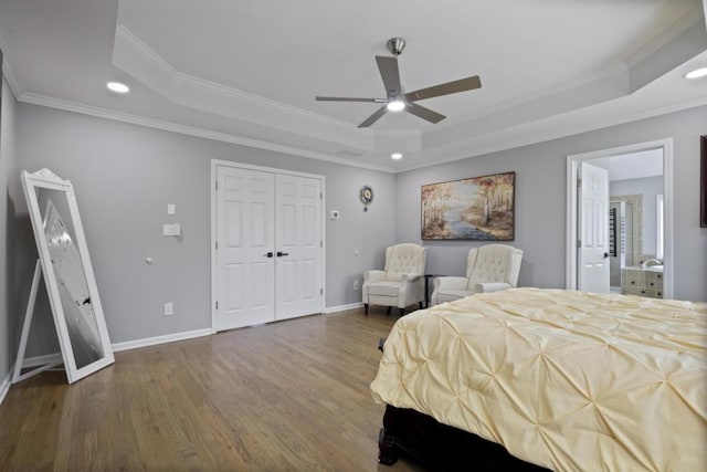 bedroom with a tray ceiling, wood finished floors, and baseboards