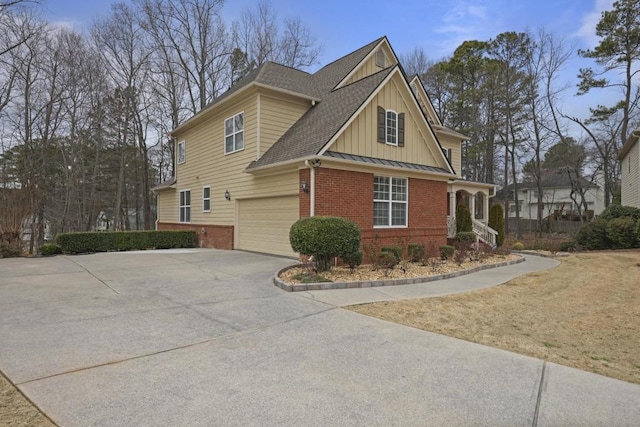 view of side of home featuring brick siding, concrete driveway, an attached garage, board and batten siding, and a standing seam roof