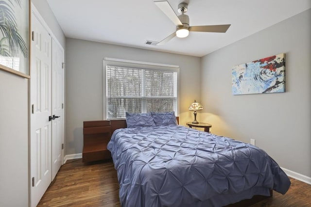 bedroom with a closet, visible vents, baseboards, and wood finished floors