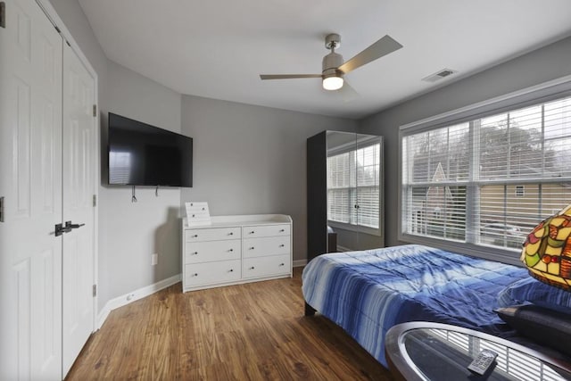 bedroom featuring visible vents, ceiling fan, baseboards, and wood finished floors