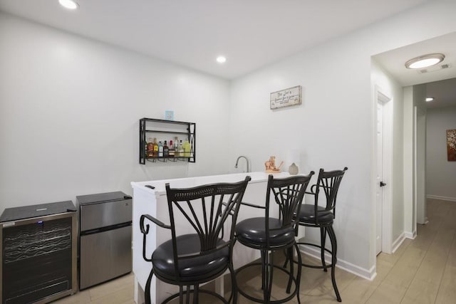 bar with baseboards, beverage cooler, visible vents, and indoor wet bar