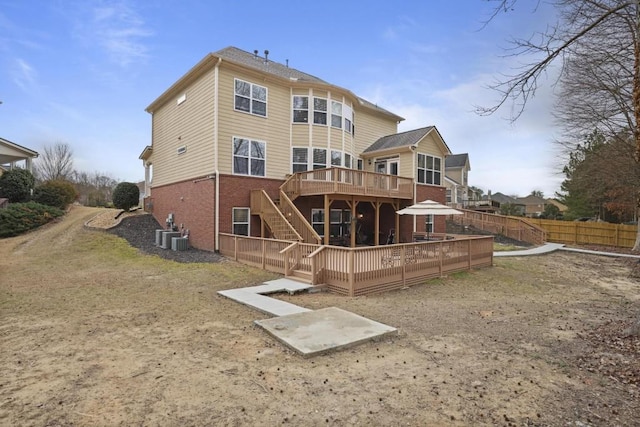 rear view of house featuring brick siding, fence, a wooden deck, stairs, and central AC unit