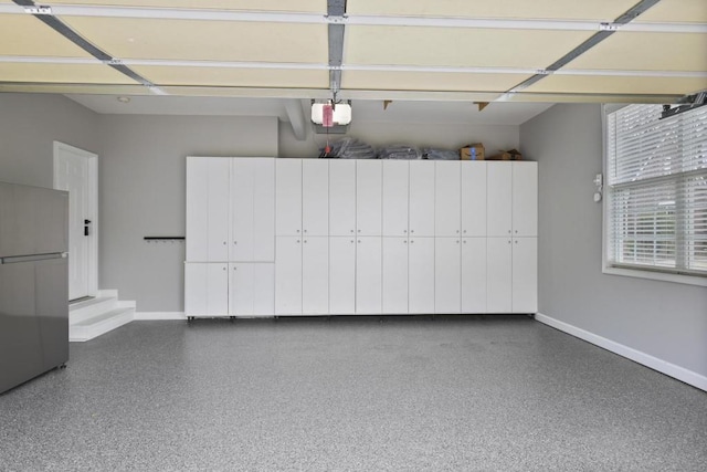 garage featuring baseboards, a garage door opener, and freestanding refrigerator
