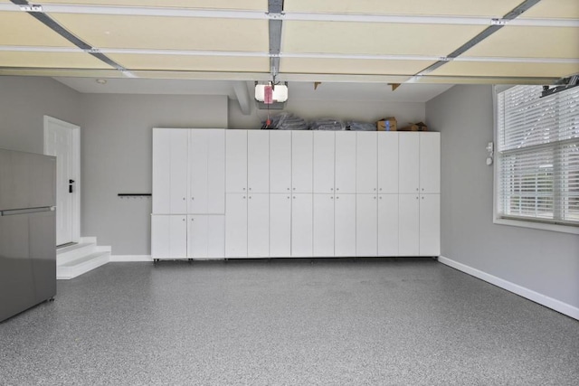 garage with baseboards, freestanding refrigerator, and a garage door opener