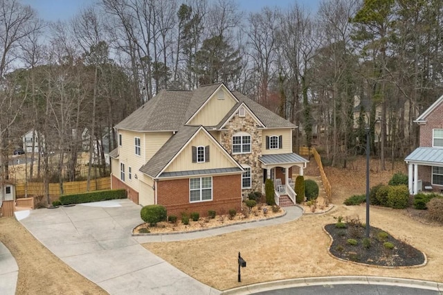 craftsman-style home featuring fence, driveway, roof with shingles, board and batten siding, and brick siding