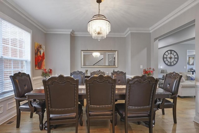 dining area with crown molding, visible vents, wainscoting, wood finished floors, and a chandelier