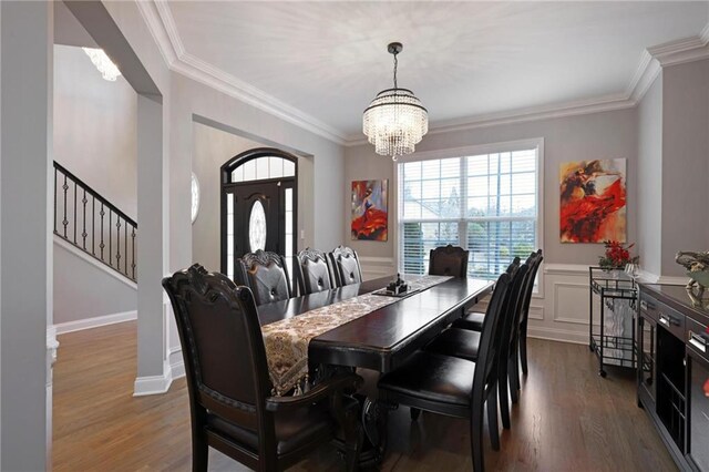 dining room with stairway, ornamental molding, wood finished floors, and a chandelier