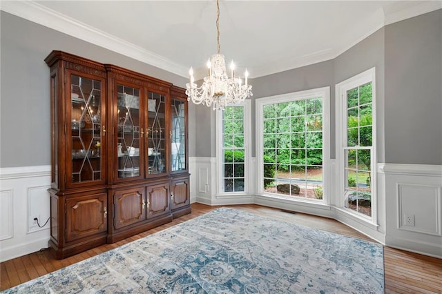 206 Kingsley Way, Woodstock, GA 30188 - unfurnished dining area with ornamental molding, a chandelier, wainscoting, wood finished floors, and a decorative wall