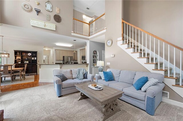 206 Kingsley Way, Woodstock, GA 30188 - living room featuring light colored carpet, stairway, a towering ceiling, and baseboards