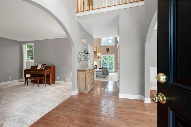 206 Kingsley Way, Woodstock, GA 30188 - foyer entrance with arched walkways, a high ceiling, baseboards, light wood finished floors, and ornamental molding