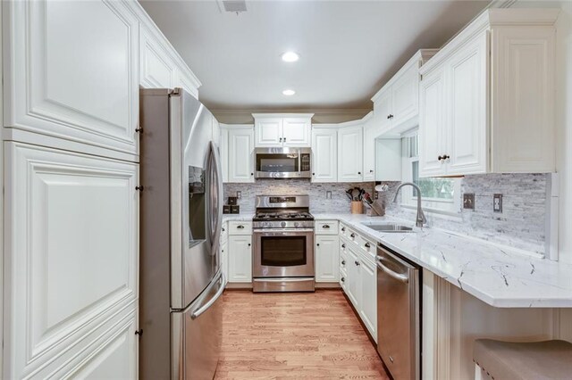 1123 Seaboard Ave NW, Atlanta, GA 30318 - kitchen featuring light wood-style flooring, white cabinetry, a sink, and appliances with stainless steel finishes
