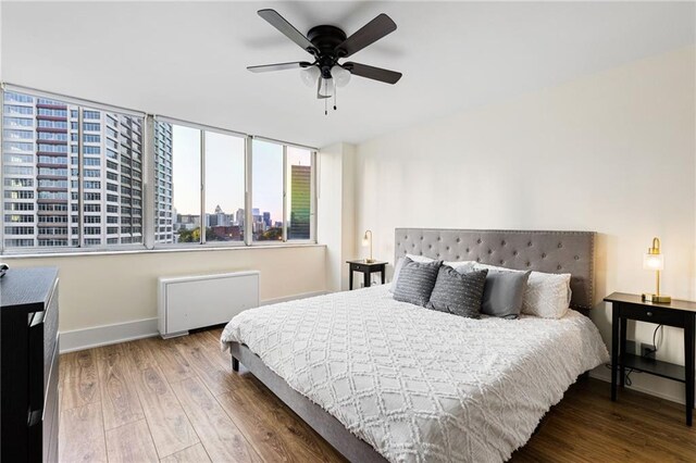 bedroom with radiator heating unit, hardwood / wood-style flooring, and ceiling fan