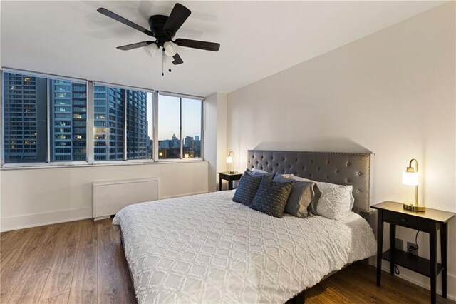 bedroom featuring ceiling fan, radiator heating unit, and dark wood-type flooring