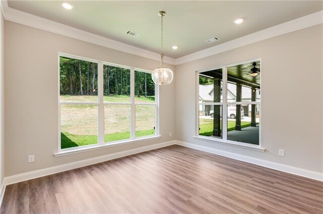 unfurnished dining area with hardwood / wood-style flooring, crown molding, and a chandelier