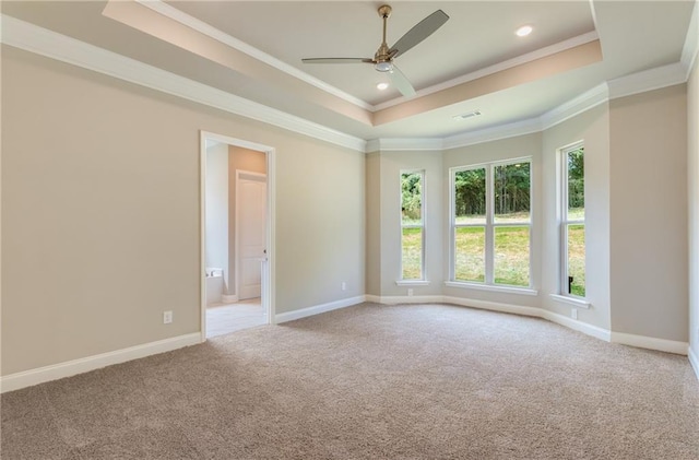 carpeted empty room featuring ceiling fan, ornamental molding, and a tray ceiling