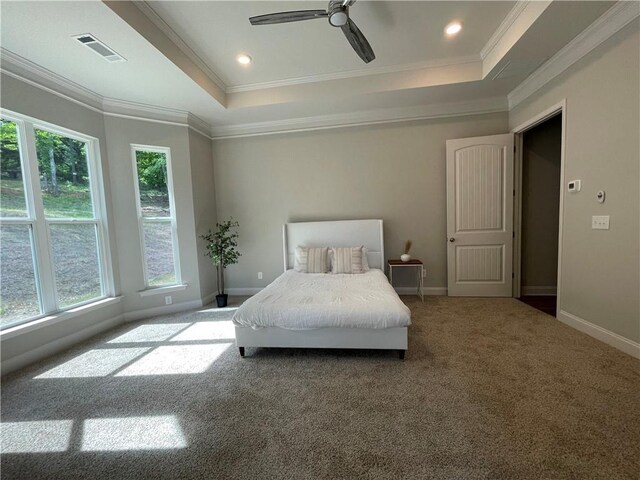 carpeted bedroom featuring a tray ceiling, ornamental molding, and ceiling fan