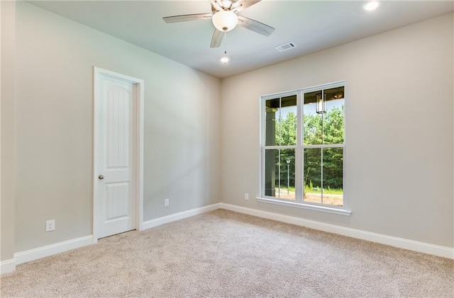 spare room featuring ceiling fan, light colored carpet, and plenty of natural light