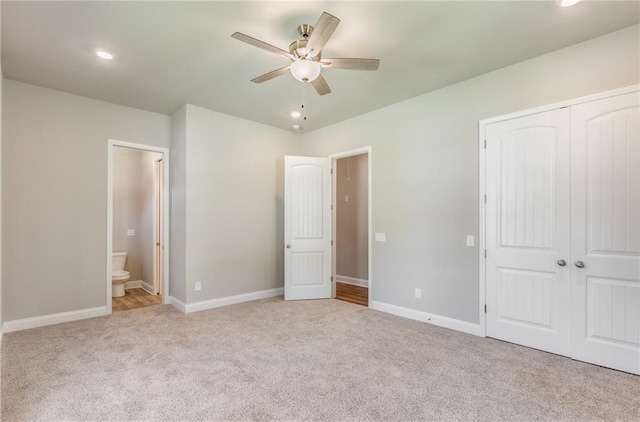 unfurnished bedroom featuring connected bathroom, light colored carpet, ceiling fan, and a closet