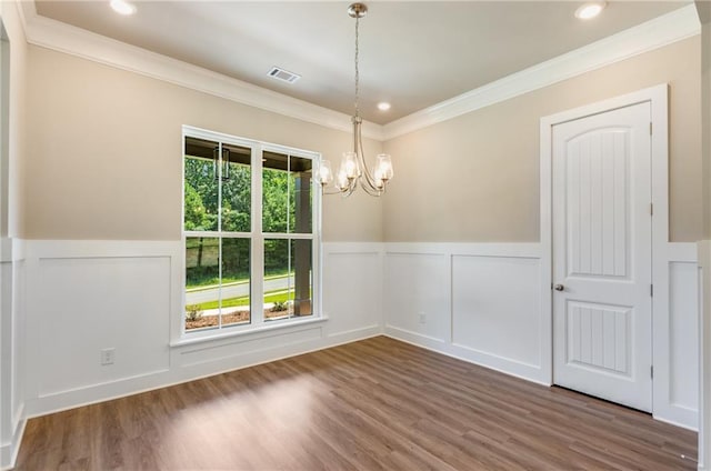 spare room with dark wood-type flooring, ornamental molding, and a chandelier