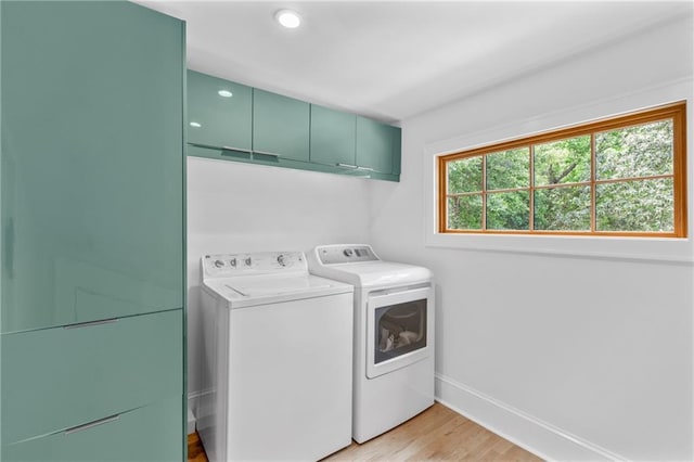 washroom with cabinets, independent washer and dryer, and light hardwood / wood-style flooring