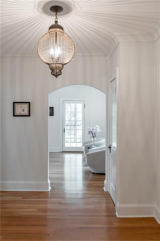 corridor with crown molding, a chandelier, and hardwood / wood-style flooring