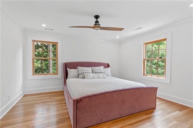 bedroom featuring light hardwood / wood-style flooring, ceiling fan, crown molding, and multiple windows