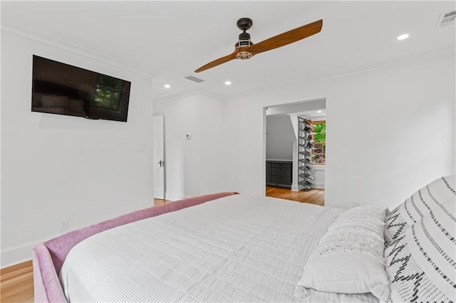 bedroom with ceiling fan, crown molding, a spacious closet, and light hardwood / wood-style floors