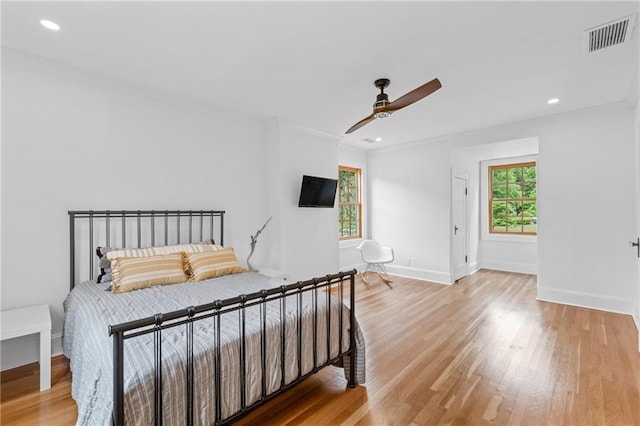 bedroom featuring multiple windows, ornamental molding, light wood-type flooring, and ceiling fan