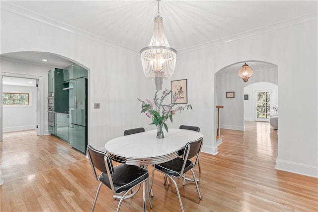 dining room with ornamental molding, plenty of natural light, a chandelier, and light hardwood / wood-style flooring