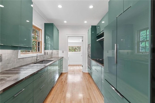 kitchen featuring green cabinets, tasteful backsplash, light hardwood / wood-style floors, and sink