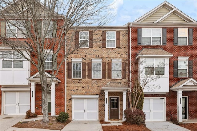 view of property with brick siding, driveway, and a garage