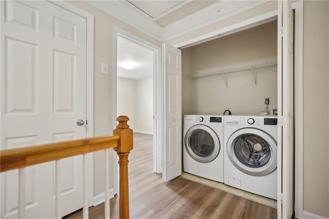 washroom featuring washer and dryer, attic access, wood finished floors, and laundry area