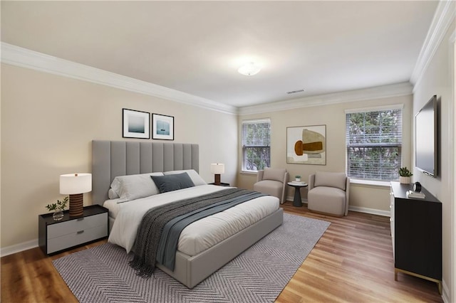 bedroom featuring light wood-type flooring, baseboards, visible vents, and crown molding