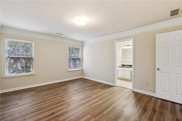 unfurnished bedroom featuring multiple windows, visible vents, and ornamental molding