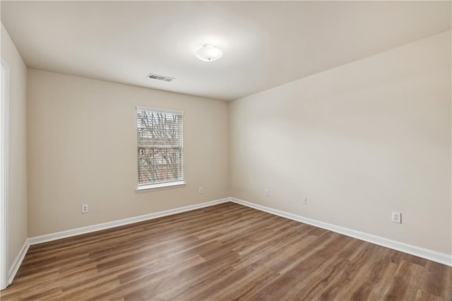 empty room with visible vents, baseboards, and wood finished floors