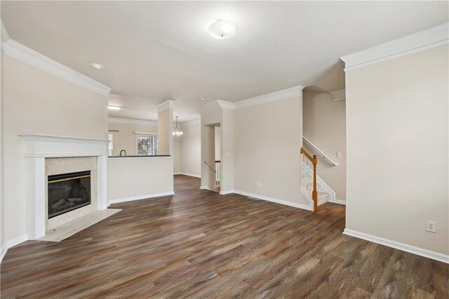 unfurnished living room featuring a premium fireplace, crown molding, and dark hardwood / wood-style flooring