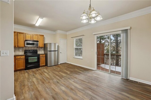 kitchen featuring hardwood / wood-style flooring, ornamental molding, appliances with stainless steel finishes, and backsplash