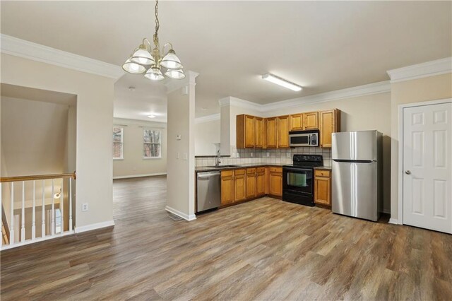 kitchen featuring decorative light fixtures, ornamental molding, decorative backsplash, and appliances with stainless steel finishes